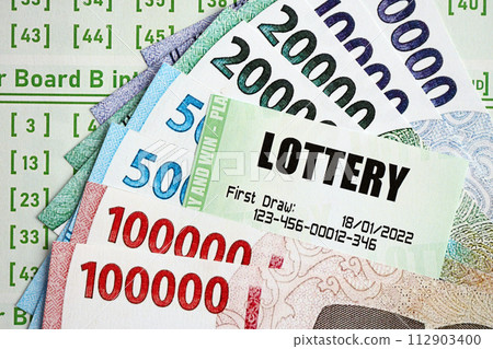 Green lottery tickets and indonesian money bills on blank with numbers for playing lottery close up Green lottery tickets and indonesian money bills on blank with numbers for playing lottery close up 112903400
