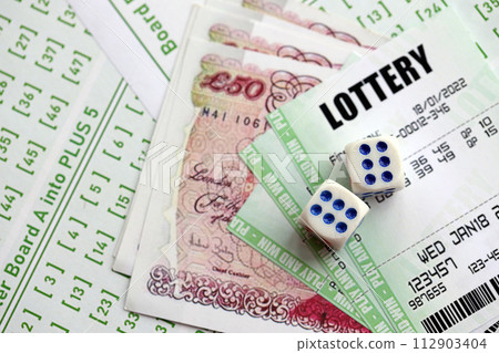 Green lottery tickets and Great Britain pounds money bills on blank with numbers for playing lottery close up Green lottery tickets and Great Britain pounds money bills on blank with numbers for playing lottery close up 112903404
