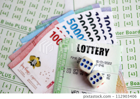 Green lottery tickets and indonesian money bills on blank with numbers for playing lottery close up Green lottery tickets and indonesian money bills on blank with numbers for playing lottery close up 112903406