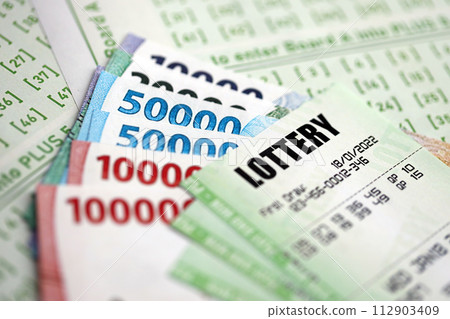 Green lottery tickets and indonesian money bills on blank with numbers for playing lottery close up Green lottery tickets and indonesian money bills on blank with numbers for playing lottery close up 112903409