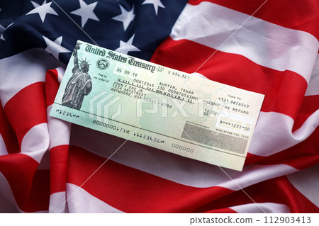 United States Treasury Refund check on waving American Flag close up. 112903413
