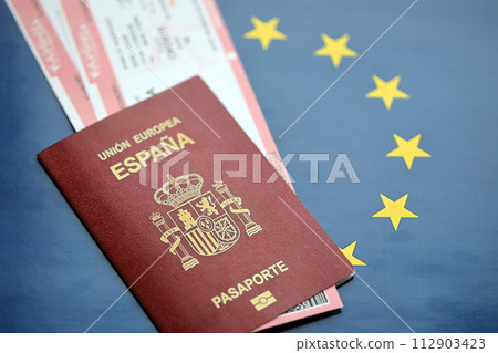 Red Spanish passport of European Union with airline tickets on blue background close up. Tourism and travel concept 112903423