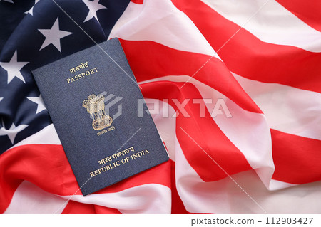 Blue Indian passport on United States national flag background close up. Tourism and diplomacy concept 112903427