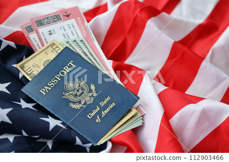 Blue United States of America passport with money and airline tickets on US flag background close up. Tourism and travel concept 112903466