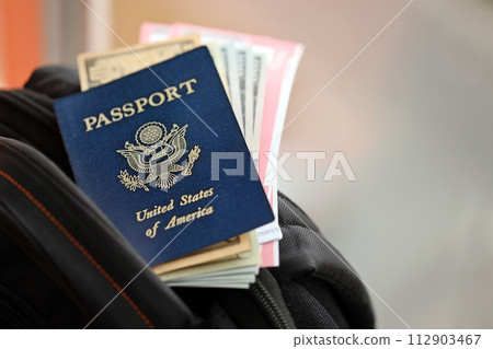 Blue United States of America passport with money and airline tickets on touristic backpack close up. Tourism and travel concept 112903467