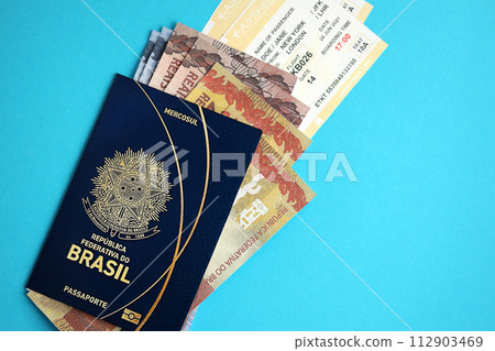 Blue Brazilian passport with money and airline tickets on blue background close up. Tourism and travel concept 112903469