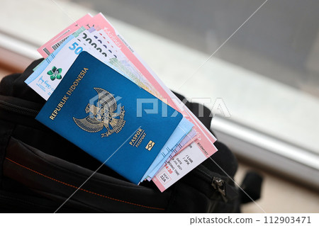 Blue Republic Indonesia passport with money and airline tickets on touristic backpack close up. Tourism and travel concept 112903471