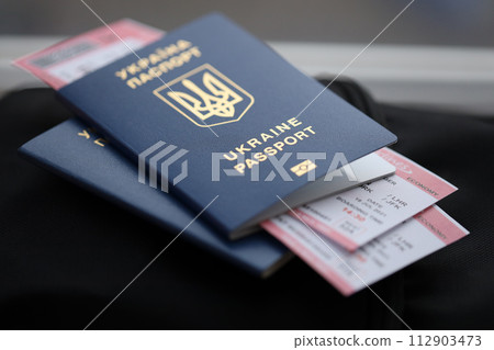 Two ukrainian biometrical passports with air flight tickets on black touristic backpack close up Two ukrainian biometrical passports with air flight tickets on black touristic backpack close up 112903473