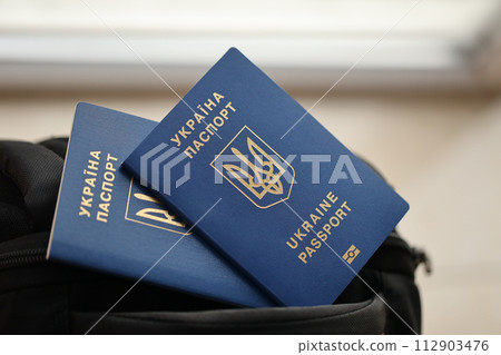 Two ukrainian biometrical passports on black touristic backpack close up 112903476