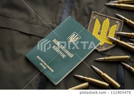 Military token or army ID ticket lies on green ukrainian military uniform indoors close up 112903478