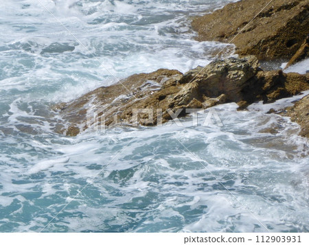 Ocean water laps volcanic rock 112903931