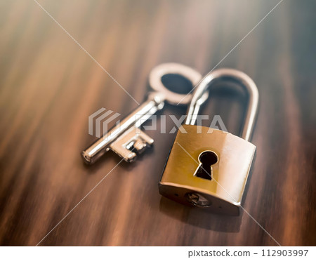 Metal padlock with a key on blurred background. Security and protection concept. 112903997