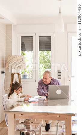 Girl playing while her grandfather working next to them 112904480