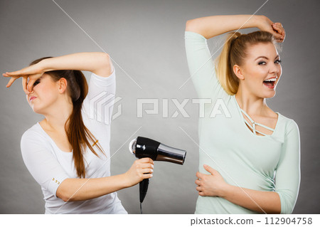 Woman drying friend armpit with hair dryer 112904758