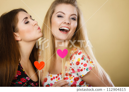 Two happy women holding heart on stick Two happy women holding heart on stick 112904815
