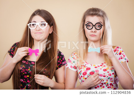 Two serious women holding carnival accessoies on stick Two serious women holding carnival accessoies on stick 112904836