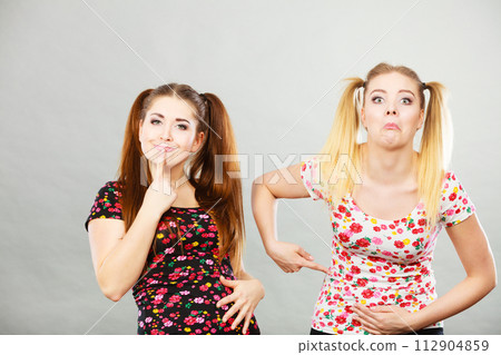 Two cheerful teenage woman holding their stomach Two cheerful teenage woman holding their stomach 112904859