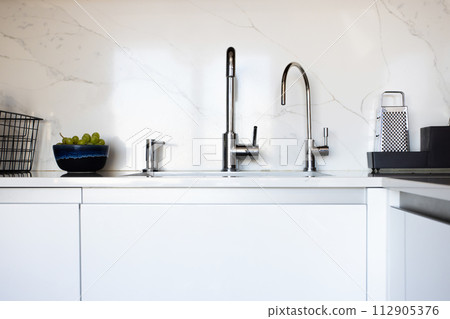 Kitchen brass utensils, chef accessories. Hanging modern kitchen with white marble wall and stone tabletop. 112905376