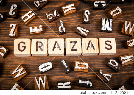 Thank you in Galician. Alphabet blocks on wood texture background Thank you in Galician. Alphabet blocks on wood texture background 112905834