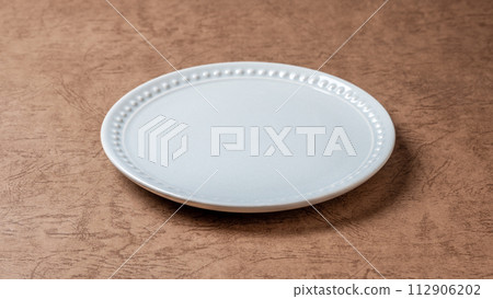 White plate/textured brown background White plate/textured brown background 112906202
