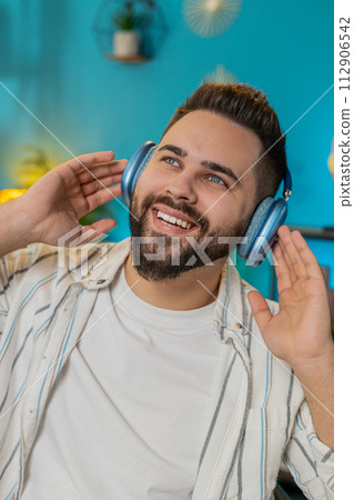 Caucasian man listening music through wireless headphones relaxing taking a break laptop on table 112906542