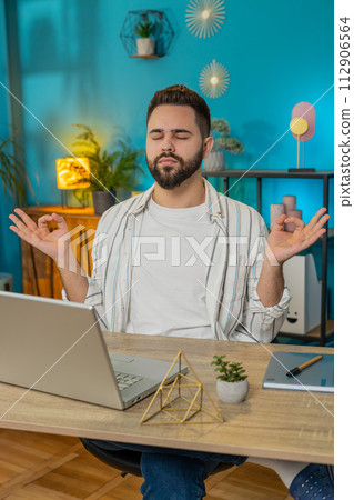 Peaceful relaxed businessman sitting at workplace with folded in mudra gesture hands meditating Peaceful relaxed businessman sitting at workplace with folded in mudra gesture hands meditating 112906564