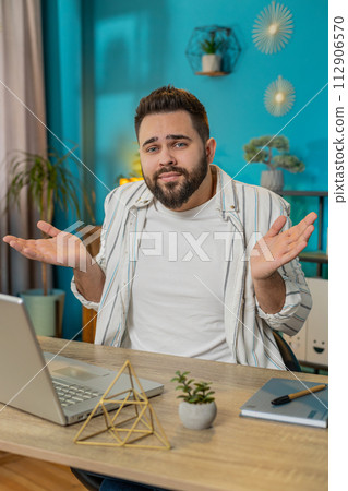 Confused man feeling embarrassed about ambiguous question having doubts no idea at home, vertical 112906570