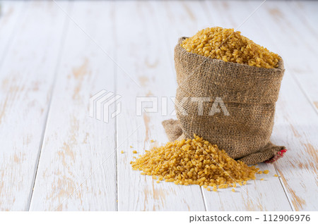 Raw bulgur in sack on a light table, selective focus. 112906976