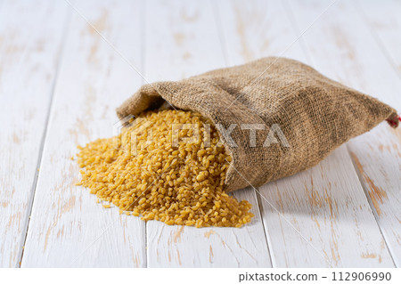 Raw bulgur in sack on a light table, selective focus. 112906990