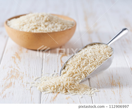 Organic white basmati rice in a metal scoop on a white wooden table. Organic white basmati rice in a metal scoop on a white wooden table. 112906997