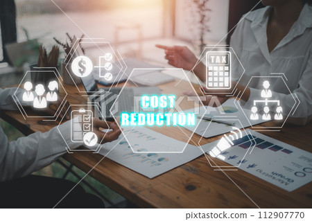 Cost reduction concept, Business team analyzing income charts and graphs on office desk with cost reduction icon on virtual screen. Cost reduction concept, Business team analyzing income charts and graphs on office desk with cost reduction icon on virtual screen. 112907770