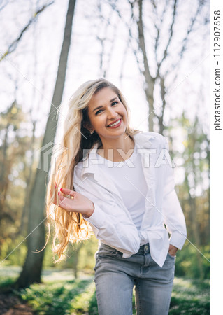 Portrait of young woman walking in spring forest.  112907858