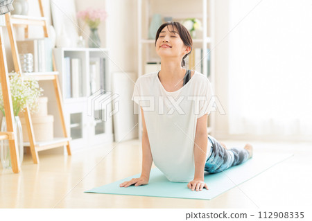 Young woman doing yoga in the living room Young woman doing yoga in the living room 112908335