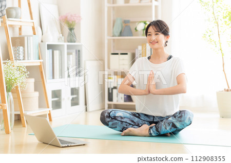 Young woman doing yoga in the living room Young woman doing yoga in the living room 112908355
