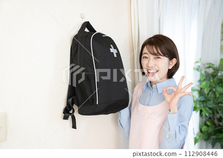 A woman with an emergency bag hanging on the wall A woman with an emergency bag hanging on the wall 112908446