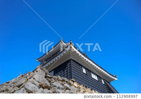 Scene of a stone walled castle with an old field view looking up against a blue sky background Scene of a stone walled castle with an old field view looking up against a blue sky background 112908997