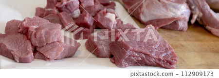 Close up of different types of peaces of meat, cutting raw meat on board kitchen. cooking. Banner 112909173