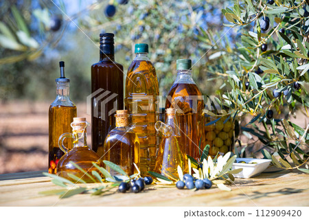 Various kinds of oil on the table on background of olive tree 112909420