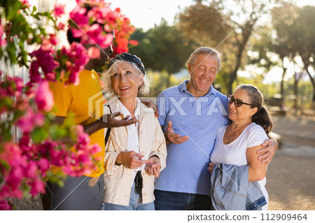 A group of friendly multiracial mixed-sex mature adult people standing outside talking to each other 112909464