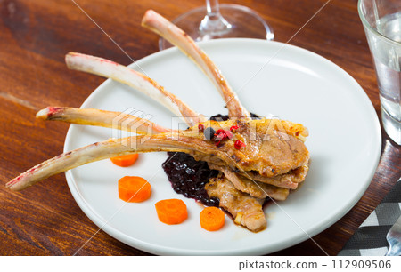 Baked rack of lamb in sauce with carrots 112909506