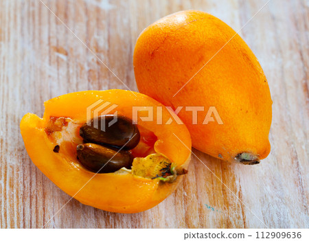 Closeup of whole ripe yellow loquat on wooden table. Vitamin fruits 112909636
