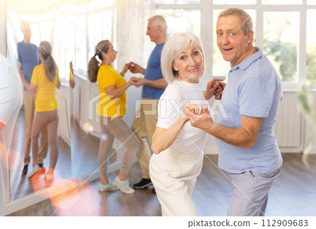 Elderly woman enjoying merengue with male partner in latin dance class 112909683