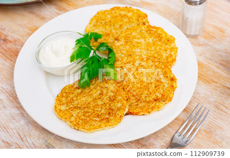Fried potato pancakes latke are neatly laid out on plate and decorated with parsley leaves. Fried potato pancakes latke are neatly laid out on plate and decorated with parsley leaves. 112909739
