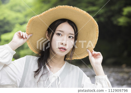 Young woman wearing a straw hat on the riverbank Young woman wearing a straw hat on the riverbank 112909796