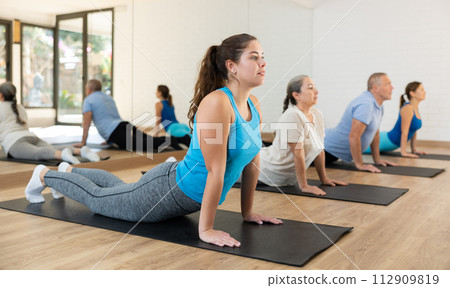 Girl doing Upward Facing Dog pose during group yoga workout 112909819
