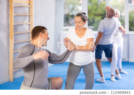 Old woman twisting her opponent's arm during self-defense classes 112909841
