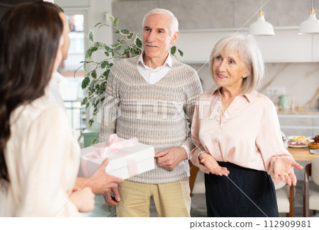 Smiling elderly couple welcoming adult children bringing gift 112909981