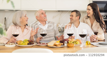 Senior couple with grown son and daughter-in-law enjoying dinner Senior couple with grown son and daughter-in-law enjoying dinner 112910294