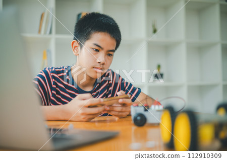 Asian boy learning and studying the work of technology robots.homeschool and science for tech project. playing childhood kids hobby leisure lifestyle people toys robotics technology. 112910309
