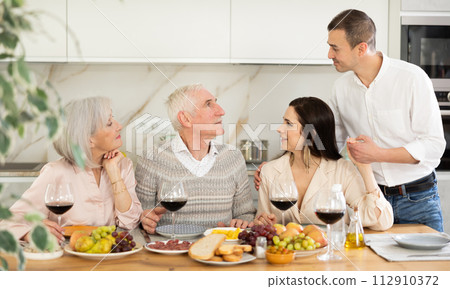 Senior couple with grown son and daughter-in-law enjoying dinner 112910372